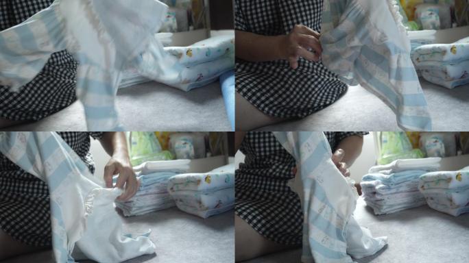母亲在家手动折叠婴儿服装概念