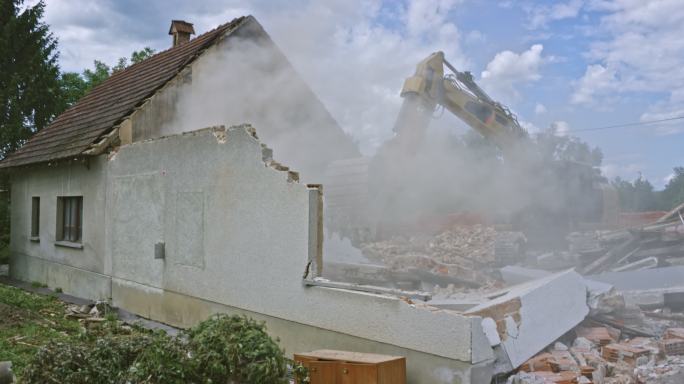 挖掘机推倒郊区的一栋旧房子的外墙