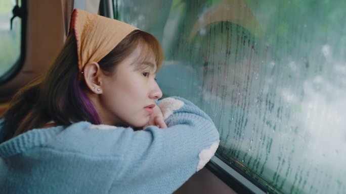 孤独的女人透过窗户看着雨。