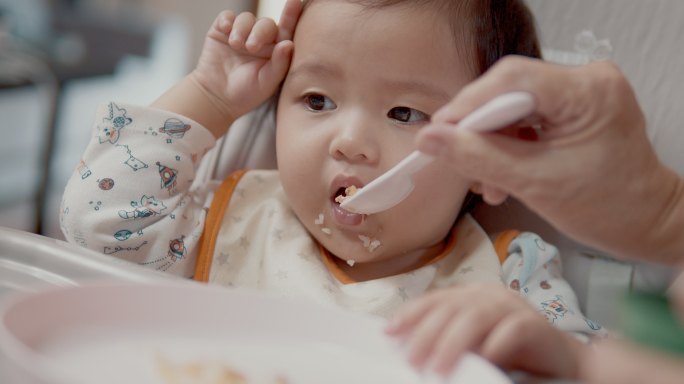 正在吃妈妈喂的食物的女婴。