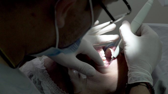 牙医戴着口罩和生物安全设备在办公室照顾病人，以避免新冠病毒19的传播