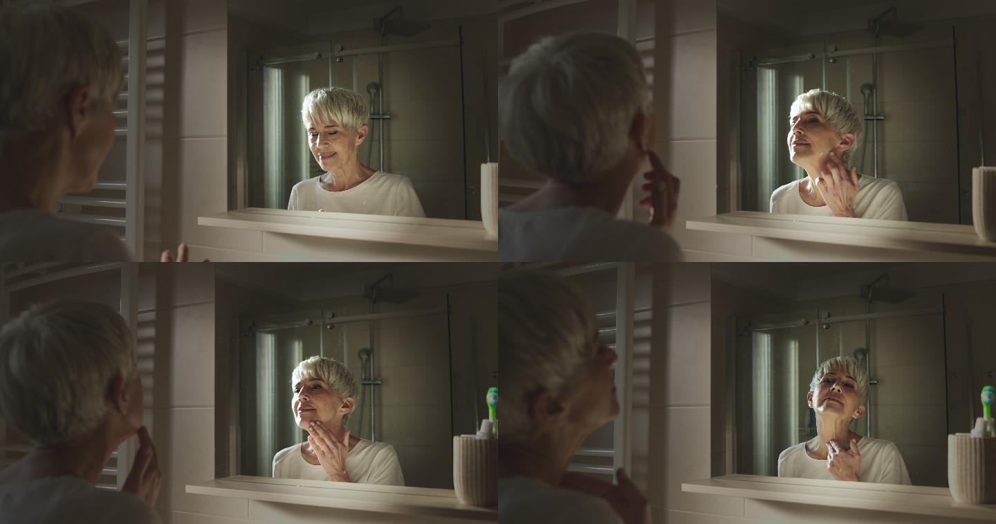 微笑的老妇人在浴室里涂抗衰老面霜。