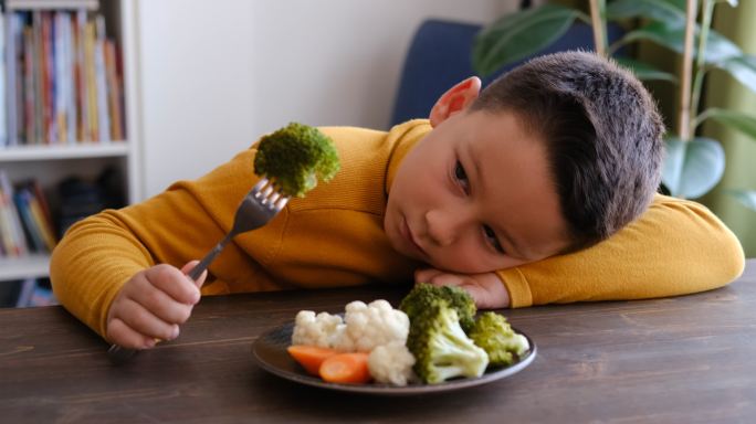 这孩子对不得不吃蔬菜很不高兴。他的盘子里有很多蔬菜。他讨厌蔬菜。