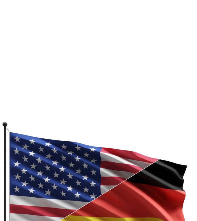 风中的美国和德国国旗在白色背景上隔离，带有复制空间