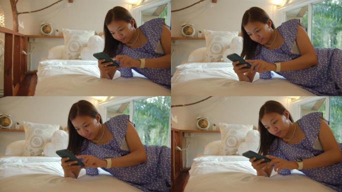 亚洲女性在家中卧室使用智能手机在线购物。