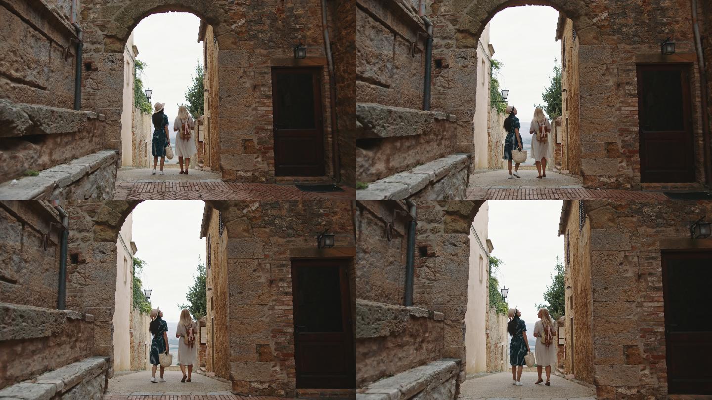 SLO MO两名女性游客穿过Pienza镇的一条狭窄小巷
