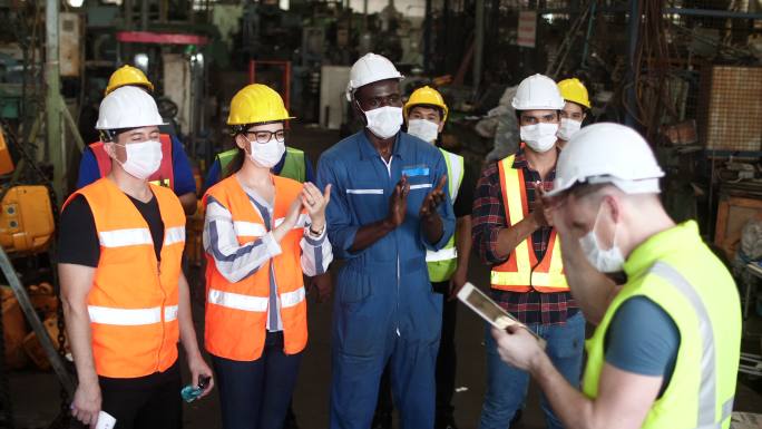 一组工厂工人在工厂佩戴防护面罩