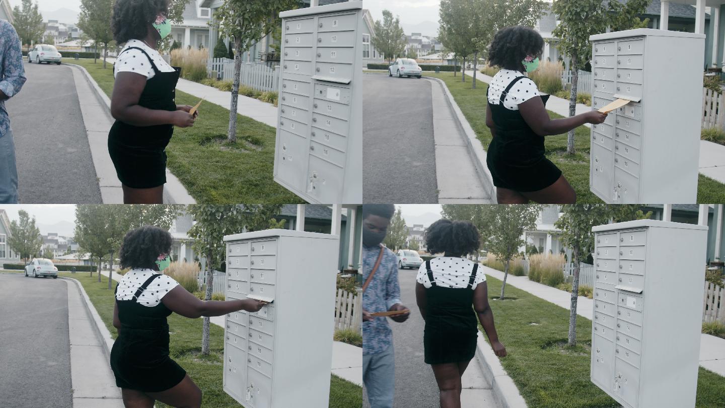 20多岁的一对年轻的非裔美国夫妇走到信箱前寄送选票
