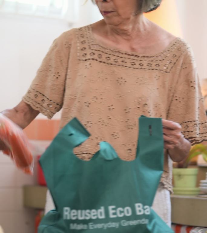 老妇人用可重复使用的购物袋购物