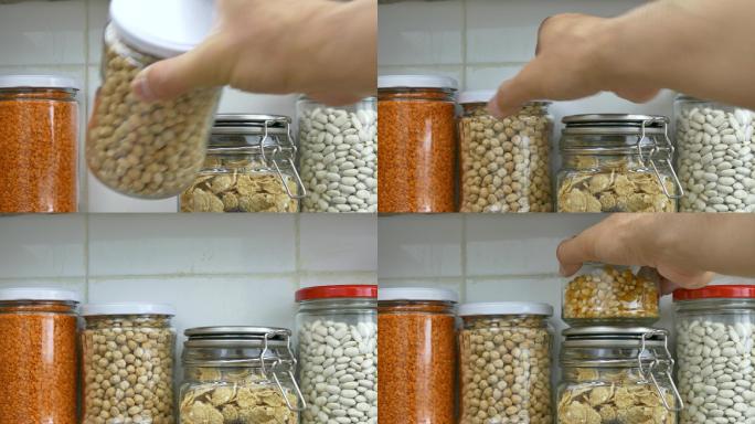 厨房食品储藏室货架上装满豆类的罐子是由一名男子整理的。