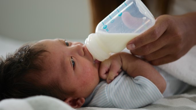 母亲在家卧室给新生儿喂奶
