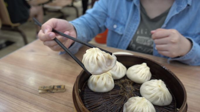 妇女们用筷子拿起小龙包饺子，蘸上酱油。