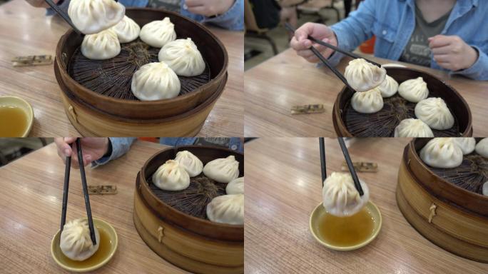 妇女们用筷子拿起小龙包饺子，蘸上酱油。