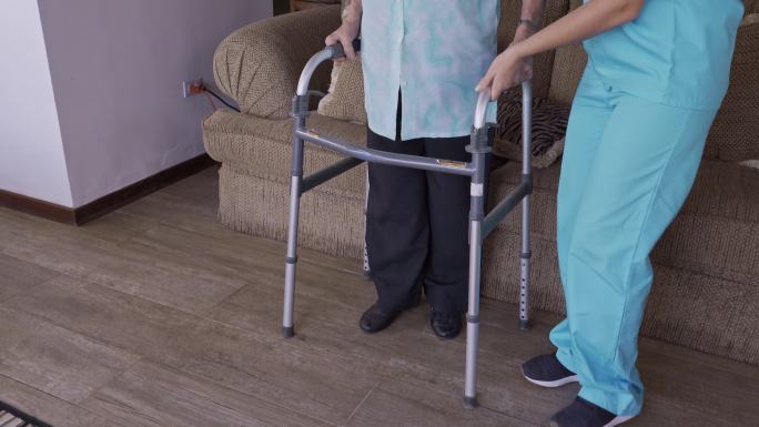 护士协助老年妇女在家使用助行器的结束