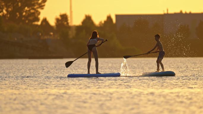 女人和男孩在河上用桨互相泼水