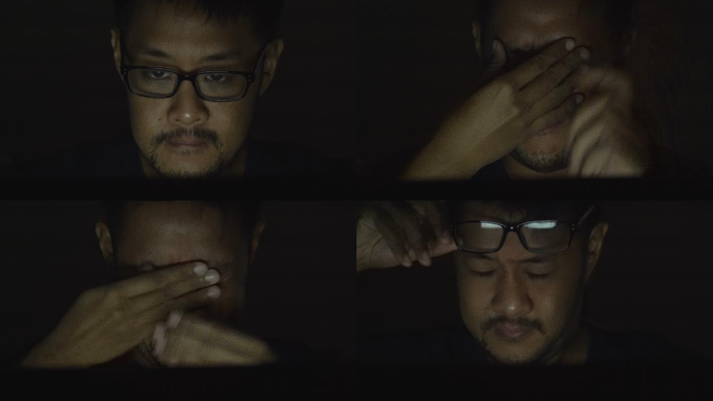 特写亚洲男子在黑暗中使用电脑伤眼睛