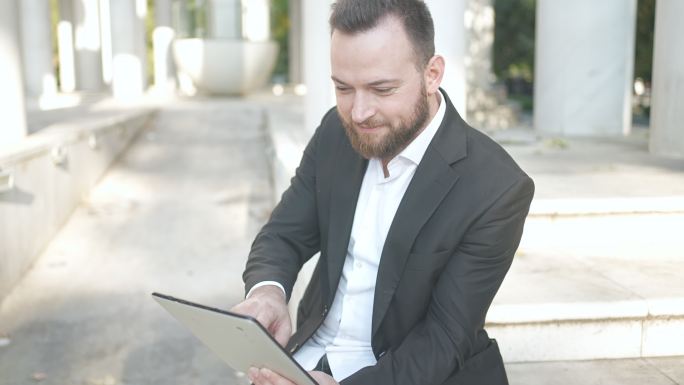 优雅的男性在数字平板电脑上欣赏音乐，外部配有耳机