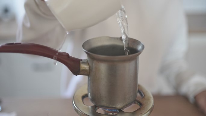 女性在水壶里倒水煮咖啡