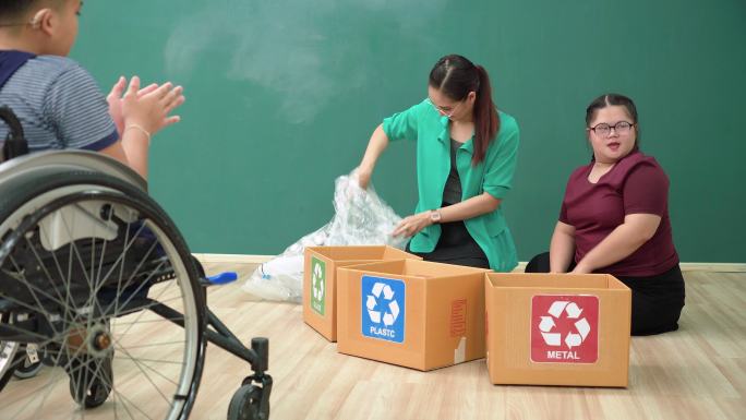 青少年唐氏综合症女孩在轮椅上与残疾学童小组学习分离回收废物，亚洲美女老师教塑料饮用水、铝罐、玻璃瓶可