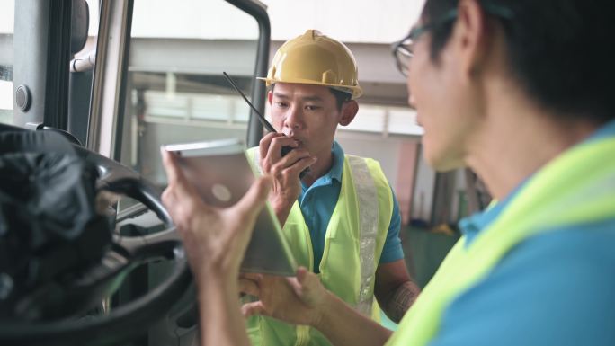 亚裔中国半卡车司机与工厂仓库工人就交货装货清单进行沟通