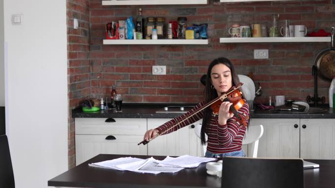 女小提琴手练习她演奏的乐曲的节奏和旋律。