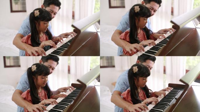 年轻的亚洲父亲在家教女儿弹钢琴