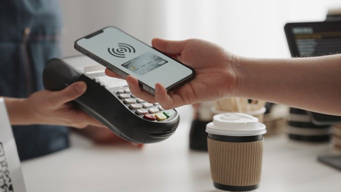 手持式移动电子钱包应用的特写镜头在信用卡读卡器上进行非接触式支付