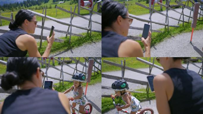 骄傲的妈妈用手机拍摄骑自行车的女儿