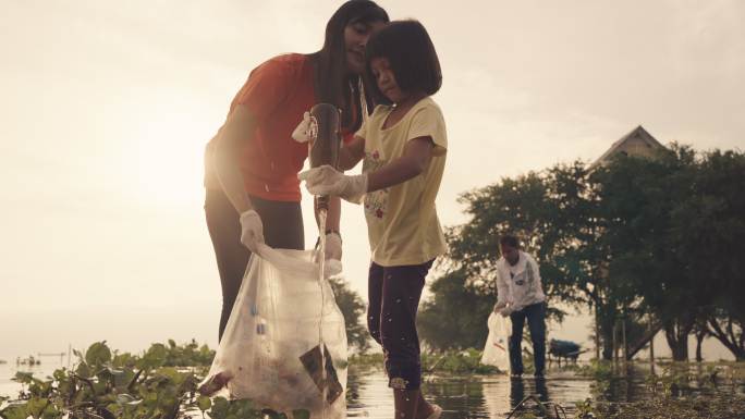 晚上，亚洲志愿者家庭在河边收集塑料瓶和水葫芦。