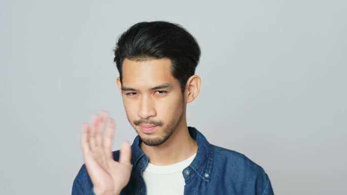照片中，一名年轻的亚洲男子站在工作室的灰色背景上，脸上流露出失望的表情，分辨率为4k