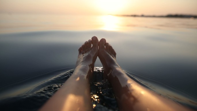 暑假里，赤脚女人在海上放松。坐在船上时，女人的脚在水中