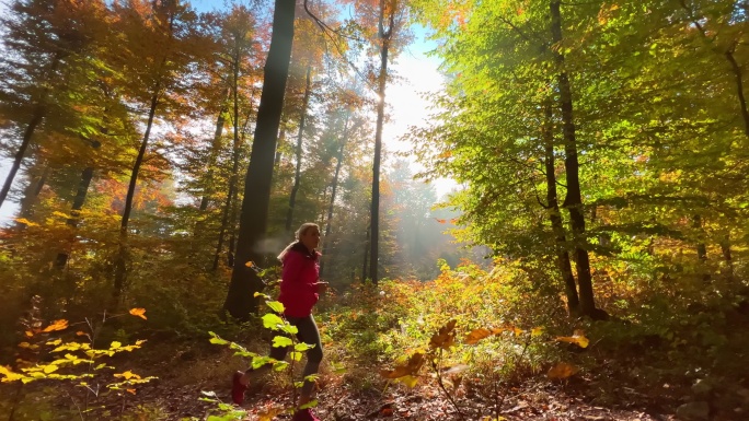 在一个阳光明媚的秋日，一个女人沿着林间小路奔跑