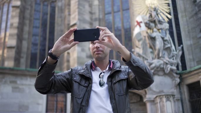 现代男性游客用手机拍摄维也纳圣斯蒂芬斯大教堂的照片