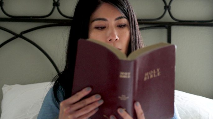 微笑的东亚妇女在家读圣经