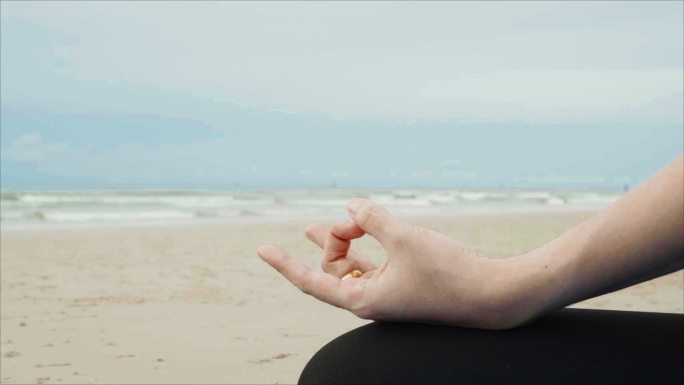 在瑜伽垫上做瑜伽和冥想的女人。早上，亚洲女性在海天多云的海滩上穿着运动服。