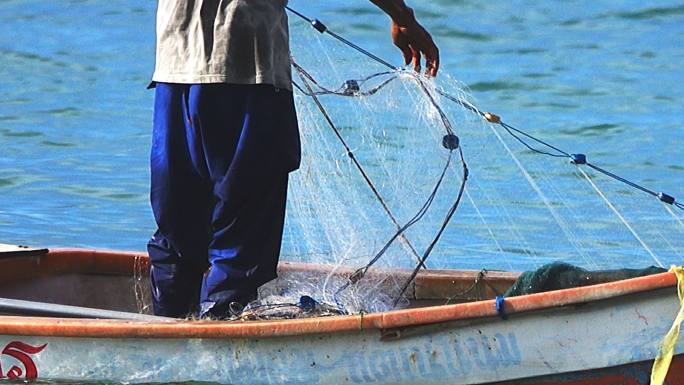 渔民在工作，在渔船上收集渔网