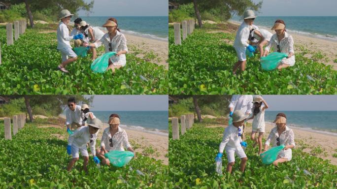 快乐亚洲大家庭与垃圾袋一起清理海滩上的区域。