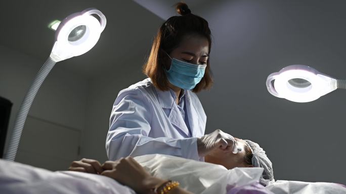 中国亚裔女护士在患者面部应用面部凝胶麻醉剂
