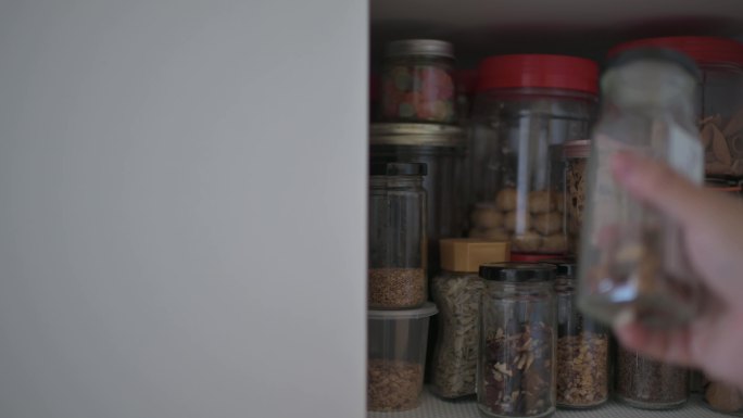 亚裔中国男性从厨房货架橱柜中取出食品瓶