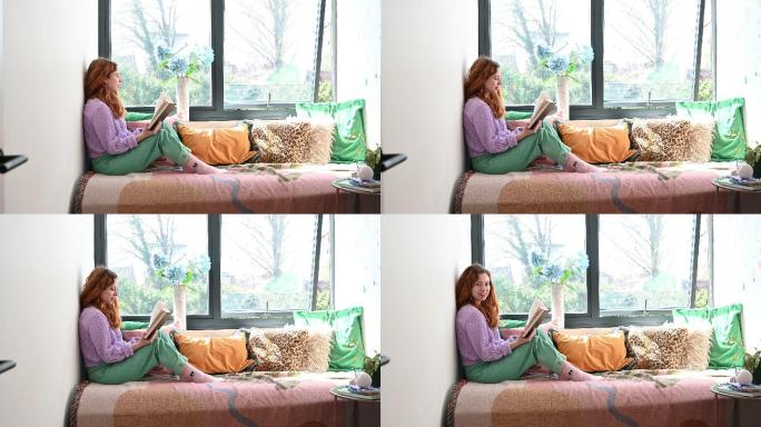 中年红发女子在阳光明媚的窗户壁龛里看书