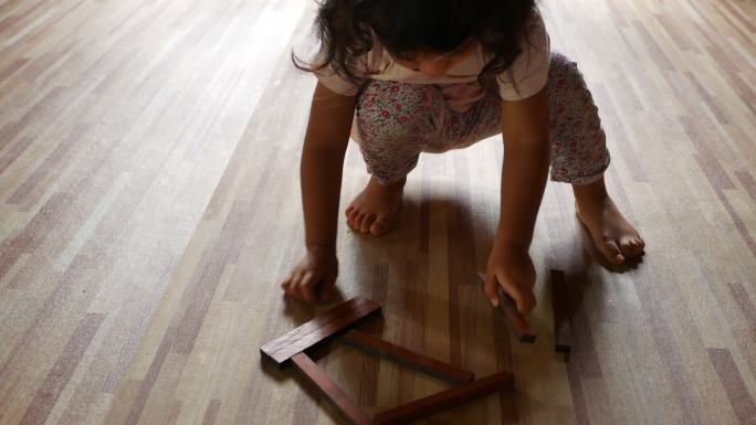 小女孩在家里用木块在地板上玩耍
