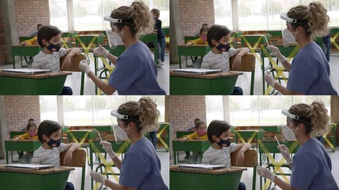 女护士在课堂上给可爱的小男孩接种新冠肺炎疫苗