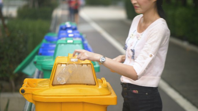 亚洲女性将塑料瓶扔进垃圾桶