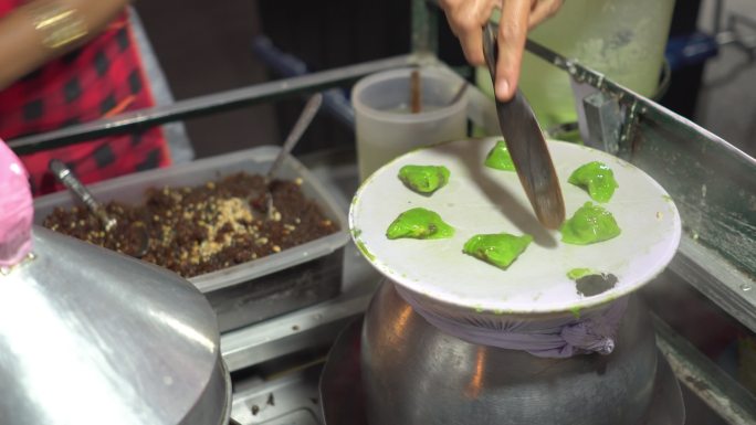 泰国厨师在泰国著名的夜间旅游目的地之一楠的当地步行街上亲手烹饪当地街头美食、泰国蒸米饭和带油炸大蒜和