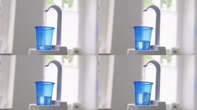 水龙头将蓝色一次性杯子装满水