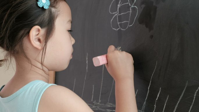 混血亚洲女孩在黑板上画画，蒙台梭利家庭教育