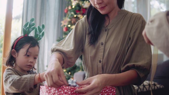 亚洲母亲和儿童帮助包装圣诞礼物。