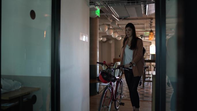年轻女商人在现代办公室骑自行车