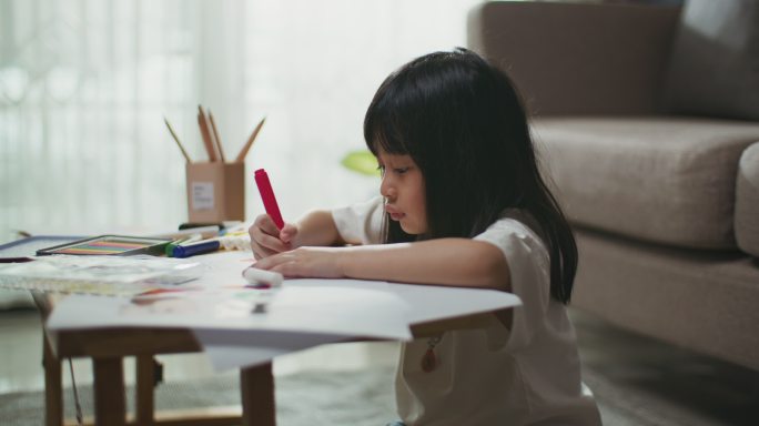 一个小女孩在客厅的桌子上选铅笔做作业