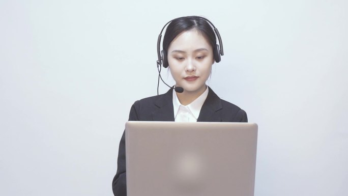 一位女性西装客服 在笔记本电脑前打电话